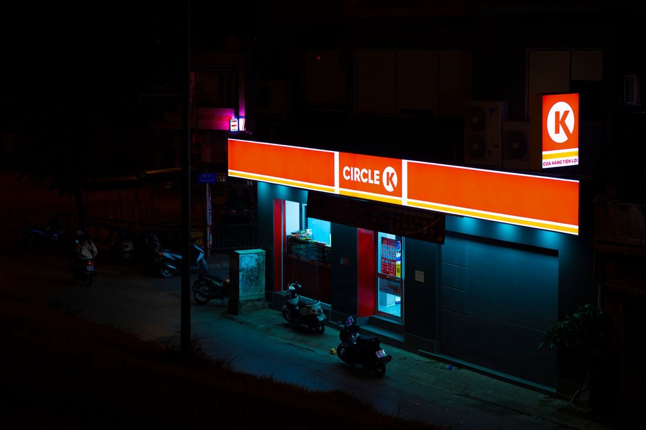 Free A high-angle view of a Circle K convenience store illuminated at night, with motorcycles parked outside. Stock Photo